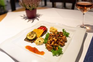 Ein Teller mit gebratenen Pfifferlingen, Gemüsetürmchen und Risotto auf einem gedeckten Tisch.