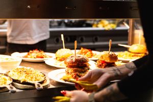Eine Wärmelampe über einer Küchentheke mit mehreren fertigen Tellern, darunter Burger und Makkaroni mit Käse.