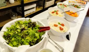 Ein langes Salatbuffet mit einer großen Schüssel frischem Blattsalat im Vordergrund und weiteren Salatschalen mit Rohkost.