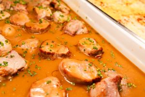 Nahaufnahme von zarten Fleischmedaillons in brauner Schnittlauchsauce im Buffetbehälter.