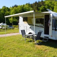 Geparktes Wohnmobil auf einer Wiese mit Esstisch und Stühlen