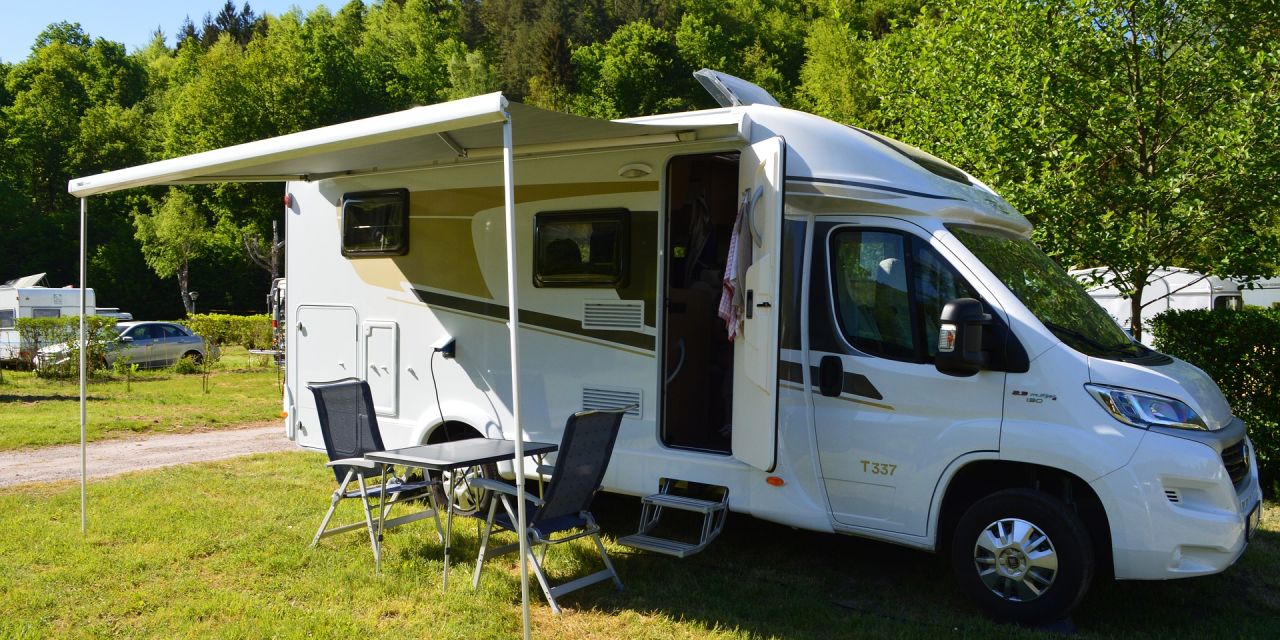 Geparktes Wohnmobil auf einer Wiese mit Esstisch und Stühlen