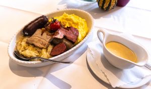 Eine ovale Schüssel mit einer Schlachtplatte, bestehend aus Sauerkraut, Kartoffelpüree, verschiedenen Fleischsorten und Wurst.