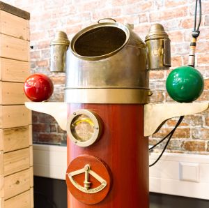 Maritimes Navigationsinstrument aus Messing mit roter und grüner Kugel vor einer Klinkerwand.