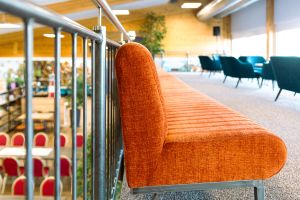 Galerie-Bereich mit orangefarbener Sitzbank hinter einem Geländer und Blick nach unten.