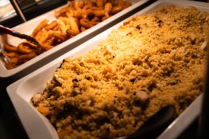 Wärmebehälter mit Couscous und Meeresfrüchten neben einer Schale mit frittierten Calamari und Garnelen.