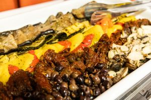 Servierplatte mit mediterranem Grillgemüse, getrockneten Tomaten, schwarzen Oliven und marinierten Champignons.